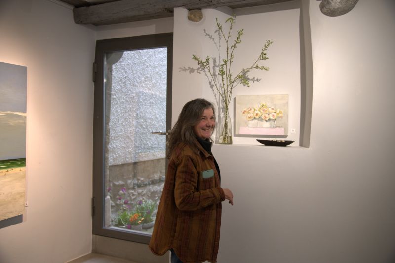 Margot Ressel neben dem Gemälde Kleine weisse Rosen an ihrer Ausstellung in der Stadtgalerie Baliere in Frauenfeld (April 2025). Foto: art24.